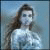 Pixelated static image of a person with long dark hair wearing a light-colored top against a blue background.