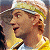 Pixelated close-up of a person with light brown hair wearing a light-colored cap, holding a yellow object near their face.