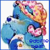Blue teddy bear with pink heart-shaped nose and yellow floral blanket, lying down with eyes closed on white background.