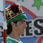 Pixelated character with green headband and patterned crown, wearing green-and-white striped shirt against blue background with red stripes and partial 'ES' text.