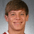 Pixelated portrait of a smiling person with short brown hair against a gray gradient background, wearing a red and white garment.