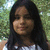 A static pixelated image shows a person with long dark hair wearing a light-colored top against a blurred green background.