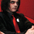 A person in a black shirt and red tie with a white emblem on the chest, against a red background, shown in three views with slight pose variations.