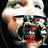 A pixelated face with a wide open mouth and eyes looking upward, showing teeth and red lips against dark background.
