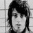 Black-and-white pixelated portrait of a person with dark hair and neutral expression against grid-patterned background.