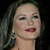 A pixelated close-up of a person with dark hair, wearing a large earring, against a dark background.