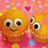 Animated orange cartoon characters with large eyes and smiles on a pink background with hearts and dots.