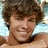 A pixelated image of a person with brown hair against a blue background, accompanied by the text He Is HOT in light blue block letters.