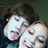 Two people in a close-up pose with pixelated text overlays on black background, one person has dark hair and the other light hair.