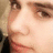 A static image with a blue background, pixelated text, and a partial face on the left side.
