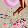 A static image shows a person's legs and feet on a sandy beach with a pink inflatable ring, displaying text 'I'M TICKLED' and 'pink' in pixelated pink font.