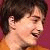 Two pixelated figures with short dark hair face each other against a maroon background, one wearing an orange top.
