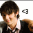 Pixelated image of a person with dark brown hair wearing a black jacket over a white shirt, with a heart symbol to the right.