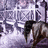 Pixelated static image with purple and white tones showing partial text fragments, a dark curved shape on the right, and light background elements.