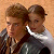Static 50x50 pixel buddy icon showing two male characters in close proximity with brown hair and dark clothing against a light orange background.