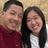 Two people pose together in a photo on the left, with green pixelated text on a black background to the right.