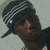 A person wearing a dark cap with white stripes and a black jacket over a light shirt, shown in four of animation