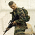 Static pixelated image of a person in military camouflage uniform holding a rifle, standing against light background with visible dithering and low-resolution artifacts.