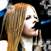 Six- of a woman with long light brown hair singing into a microphone, wearing dark sleeveless tops and wristbands against star-patterned backgrounds