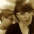 Two people in sepia-toned images with one person wearing glasses and a dark top, the other partially visible behind.