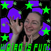 A person with short hair and glasses smiles broadly, hands raised in a waving gesture against a purple hexagonal background with green stars.