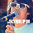 A person wearing white sunglasses and a light blue shirt holds a dark microphone with yellow accents, with the text JOSEPH overlaid in large white letters.