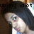 Pixelated image of a person with dark hair and light skin, wearing a white top with blue accents, overlaid with black text reading 'up: my idiot' against a brown background.