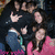 Group of people in dark and pink clothing with one person making a hand gesture, displayed in a