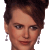 Pixelated close-up of a person with short dark hair styled upward, wearing dangling earrings, against a light gray background.
