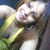 A person in a yellow and green sleeveless top with long brown hair, smiling broadly across four showing slight head movement