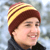 Static pixelated image of a person wearing a striped knit hat with yellow and brown stripes, visible against a blurred background.