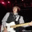 A pixelated image shows a person holding a white electric guitar against a dark background with red lights, next to a pink heart-shaped icon.