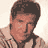 Pixelated static image of a person with dark hair and light skin wearing a tie, cropped to show upper body against a plain background.