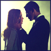 A static image shows a man and woman facing each other closely, the man's hand near the woman's face, against a bright background.