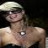 Pixelated static image of a person wearing a light-colored cap and dark sunglasses, with visible skin tone on the face and chest area.