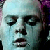 Pixelated close-up of a person's face with closed eyes, light blue skin tone, and dark hair on the right side.