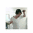 Pixelated image of a person in a white shirt holding a dark object near their face, with blurred background elements.