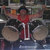 Pixelated static image shows a figure in red top and white pants holding drumsticks near large cymbals.