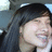 Pixelated close-up of a person with dark hair and light skin, smiling slightly against a blurred background.