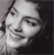Pixelated grayscale portrait of a person with short dark hair, smiling, against a dark background.