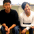 Two pixelated figures sit side-by-side; left figure wears black shirt and dark cap, right figure in white shirt with visible collar.