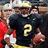 Yellow background with blue text and a pixelated image of a football player in a black jersey with yellow number 2 holding a football.
