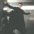 A pixelated figure in a dark coat stands with arms outstretched against a blurred background, next to green text reading "Original Icons .com" on a solid green field.