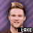 A static image of a person with light brown hair styled upward, wearing a dark shirt against a purple striped background, with text below the head.