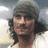 Pixelated image of a person with long dark hair and a headband, set against a red background with pixelated text elements.