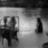 Black-and-white pixelated image showing a stylized figure with a chair and table in a room setting, with a bright light source on the right.