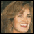 Static pixelated image of a person with light brown hair and fair skin, cropped to show upper face and shoulders against a dark background.