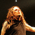 Pixelated image of a person with long light brown hair wearing dark clothing against a black background.