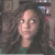 A static pixelated image shows a person with long dark hair and light skin, wearing a green top against a blurred background.