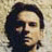 Pixelated close-up of a person with dark hair against a light textured background, showing partial facial features and clothing.